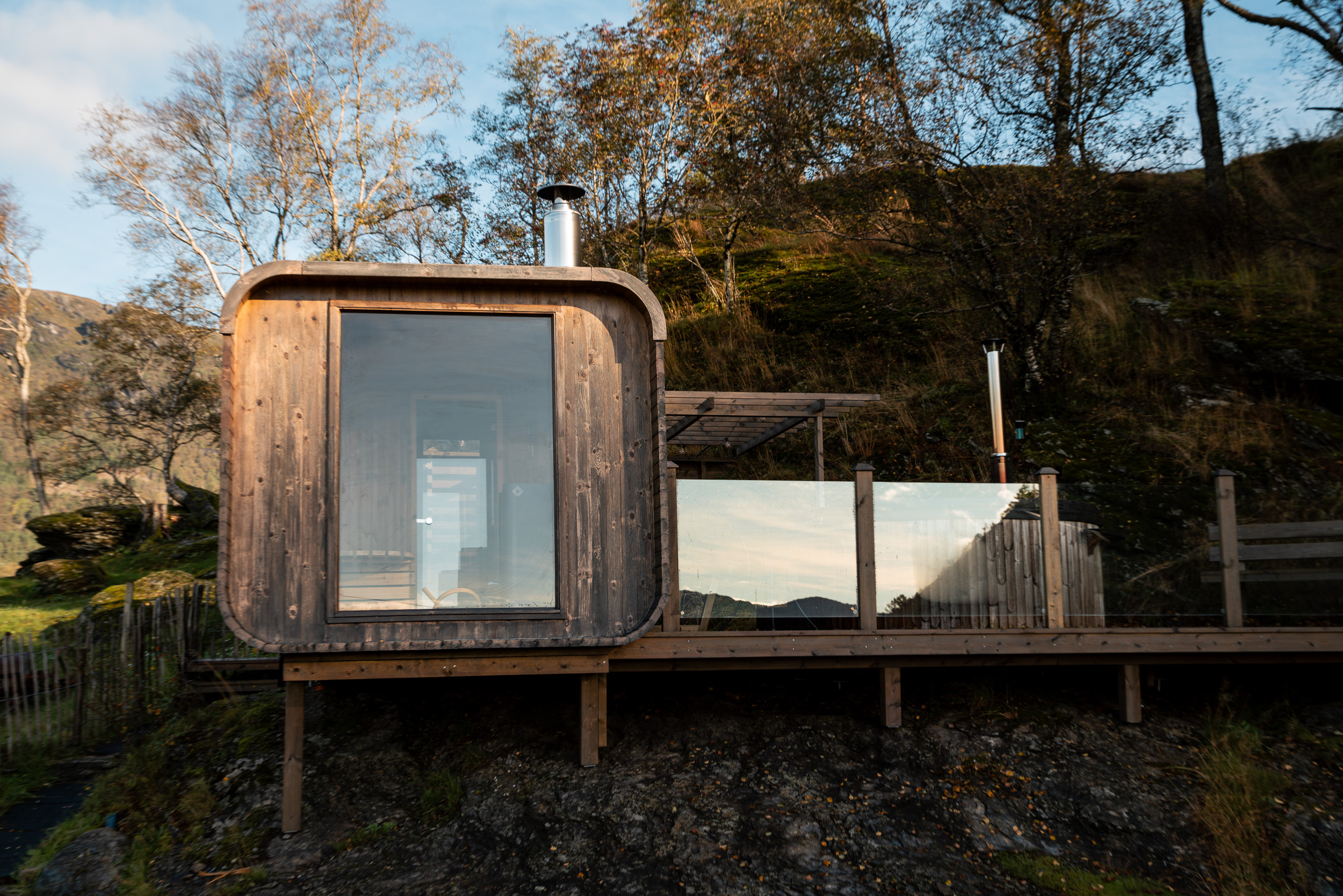 Badstuen og terrassen med badestamp i haustlys
