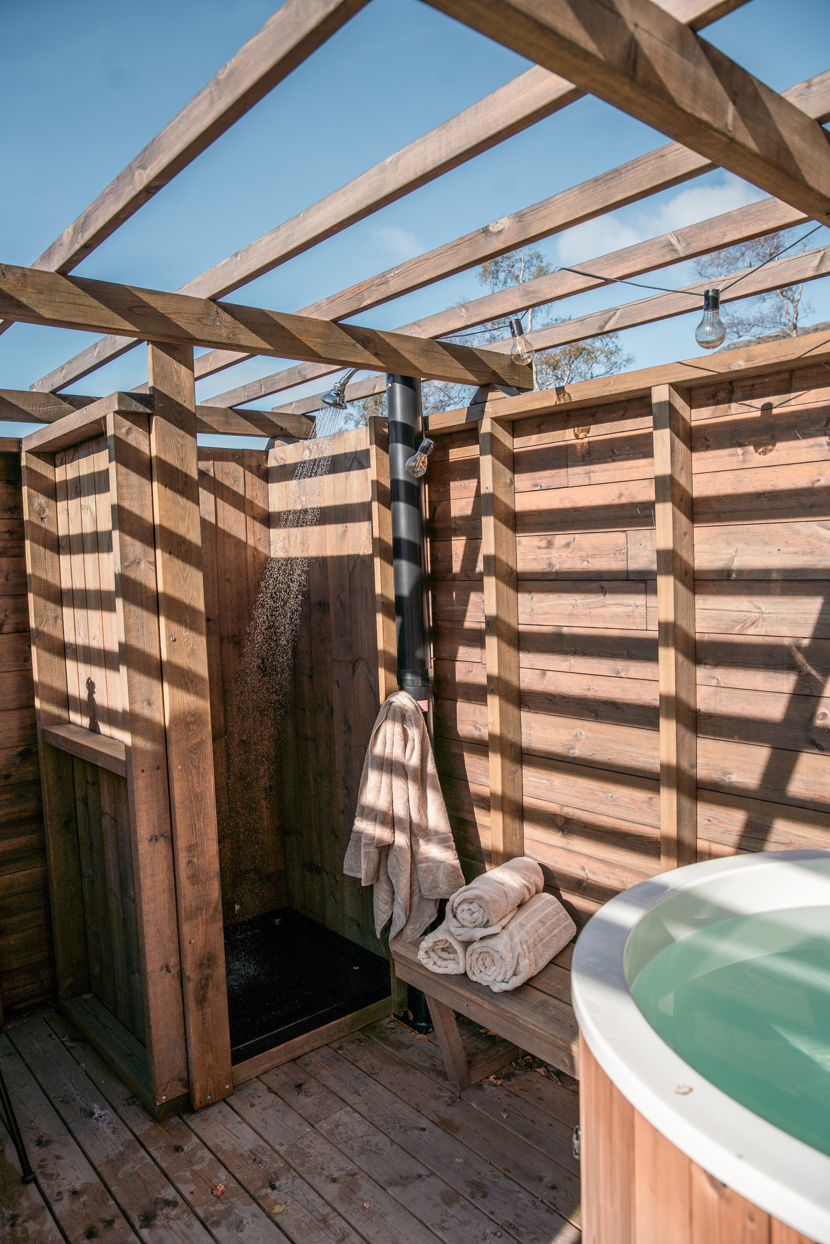 Utedusj under pergola med handklede på benken og badestamp i hjørnet
