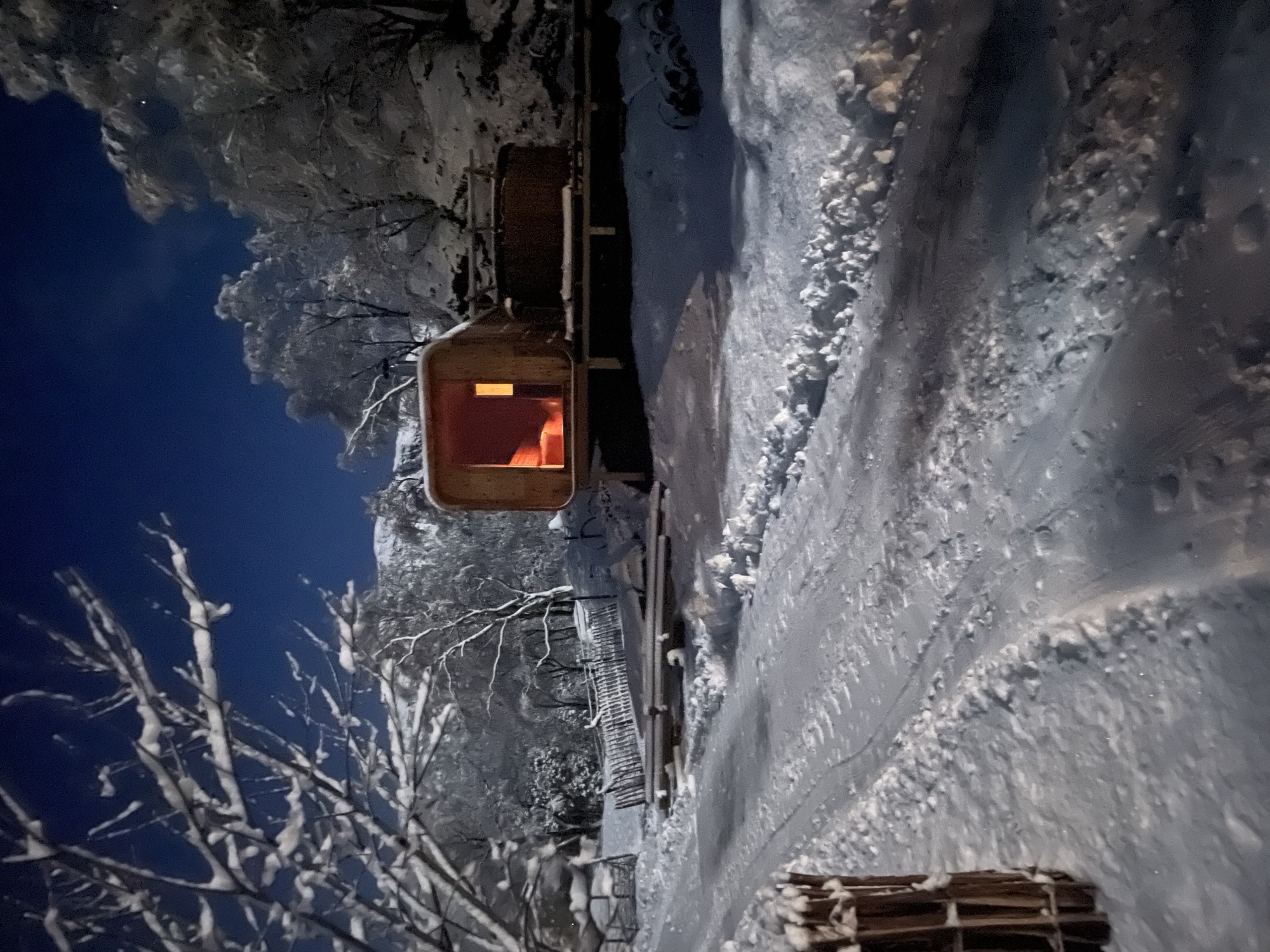 Badstuen på Øvregård ein vinternatt med varmt lys og snødekt landskap